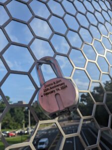 a lock hung on a bridge is engraved with a wedding anniversary date