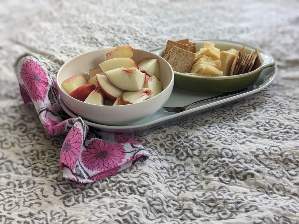 a bowl of fruit and a bowl of cheese on a white spread