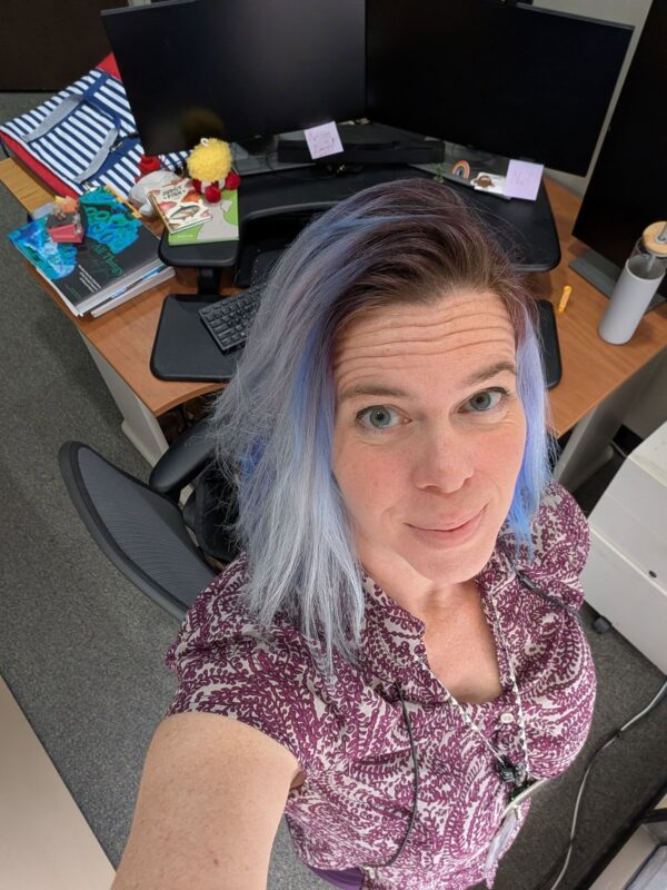 selfie of a woman looking up with a messy office desk behind and below her